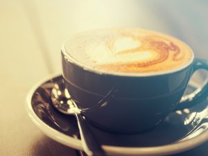 Oscar-ehdokkaat piirrettyinä kahviin Cappuccino coffee in black cup on wooden table, Soft focus, Summ