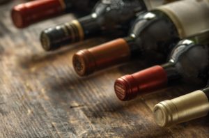 Row of wine bottles with dry red  wine on wooden background. Low depth of field. Wine making and wine shop concept.