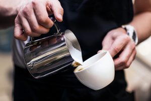 Barista making coffee pouring milk