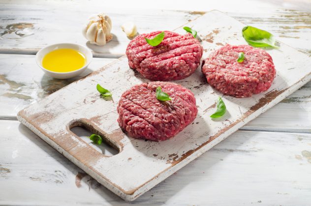 Raw Ground beef Burger steak patties on white wooden cutting boa