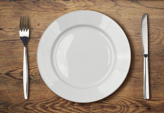 white empty dinner plate setting on wooden table