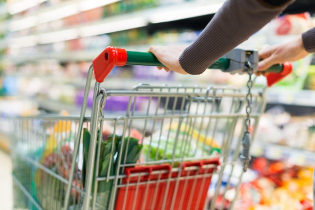 Woman driving a shopping cart in a supermarket market food