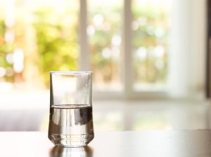 Makutestissä jätevedestä suodatettu juomavesi closeup Glass of water on table in the living room