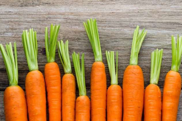 Fresh carrots bunch on rustic wooden background.