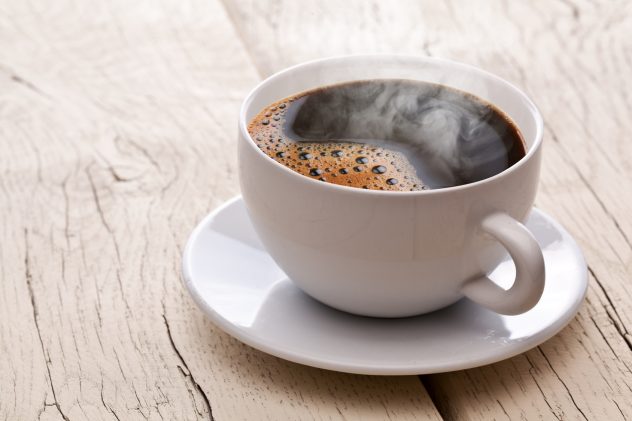 Cup of hot coffee on an old wooden table. black