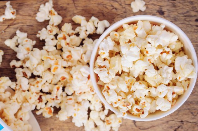 Popcorn in paper cups on wooden surface.