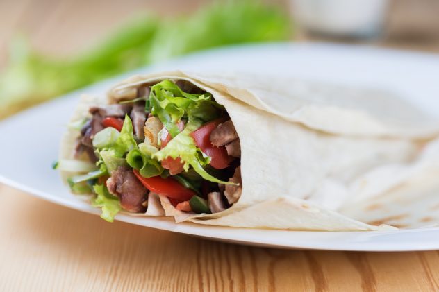 Tortilla burrito with a delicious grilled meat and fresh mixed leafy gre