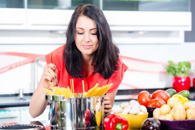 Woman cooking pasta in domestic kitchen boil spaghetti