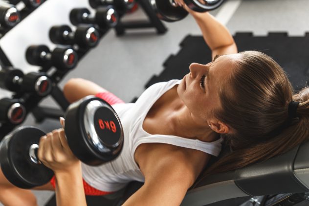 Woman lifting  weights and working on her chest at the  gym