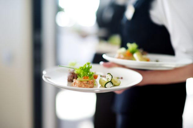 Waiter carrying plates with meat dish waitress