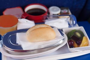 Tray of food on the plane. Focus on a bun.