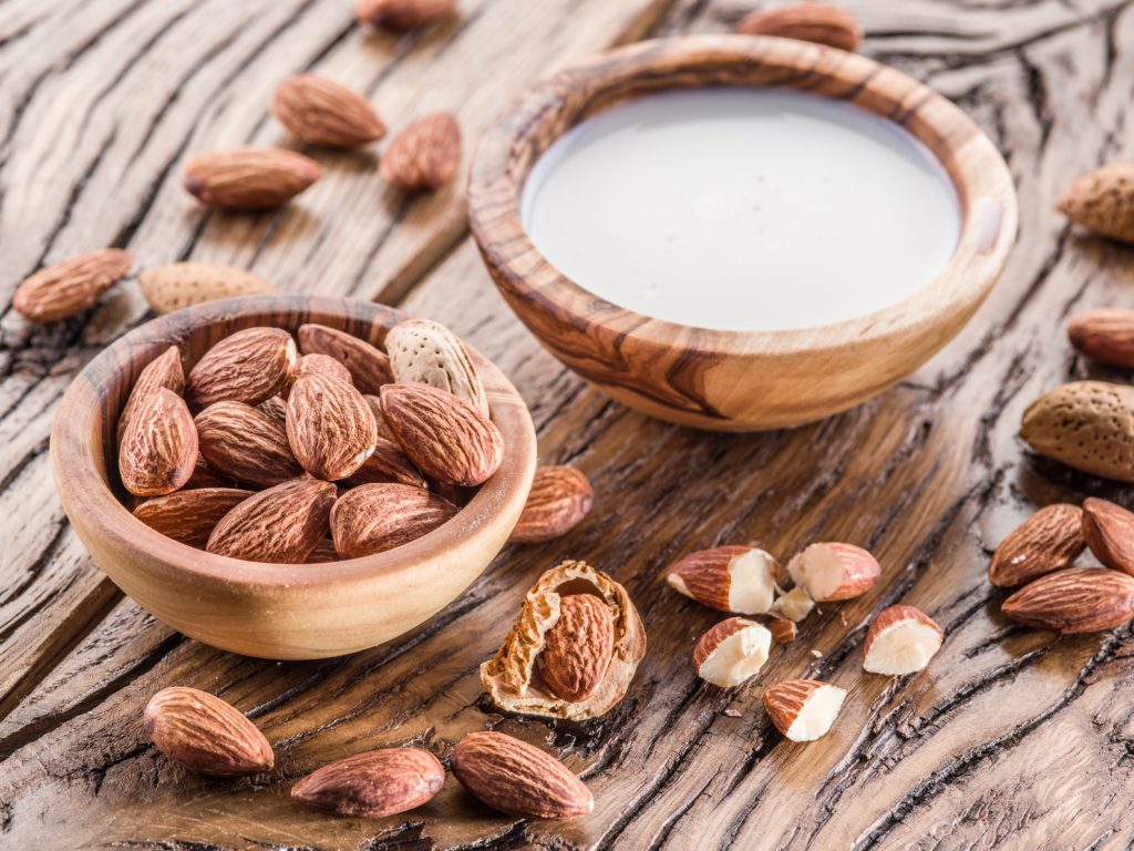 Almond nuts and milk on wooden table.