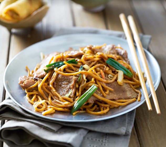 chinese food – beef lo mein on a plate with chopsticks