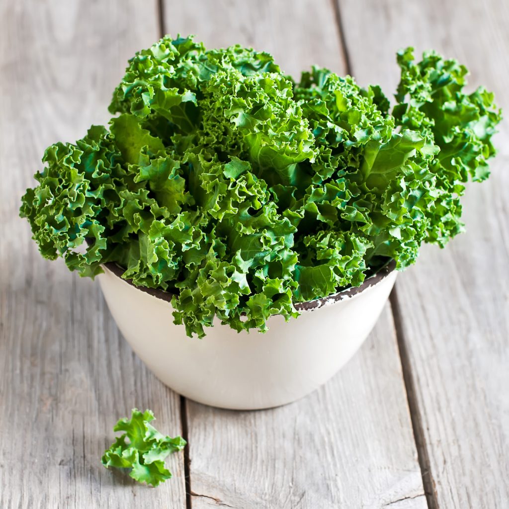 Fresh green kale in ceramic bowl. Selective focus.