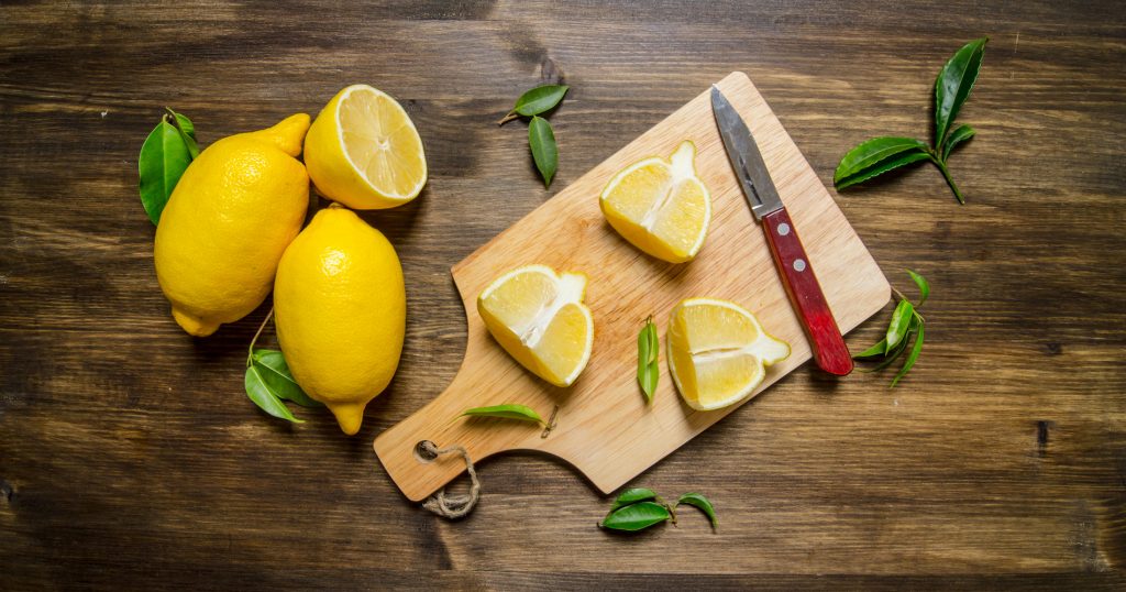 Sliced lemon on the Board with leaves. On a wooden table. Top view