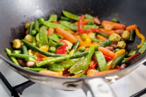 Closeup image of roasting mexican vegetables mix in wok pan side view cooking