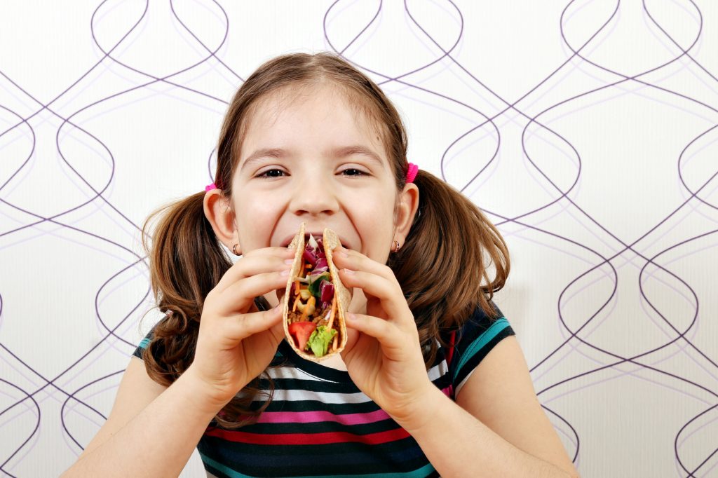 hungry little girl eating tacos