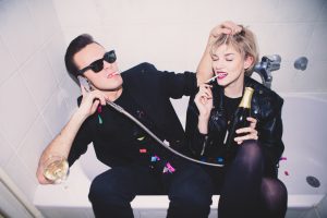 New Year’s Party. Girl and boy sitting in the bathtub drinking and having fun