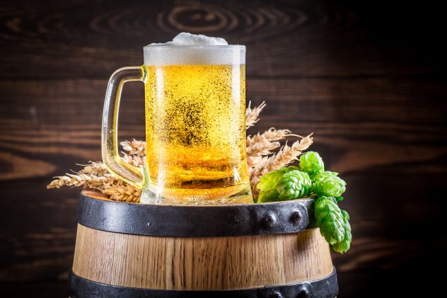 Cold and fresh beer in glass on wooden barrel