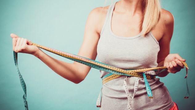 Fitness girl measuring her body with tapes