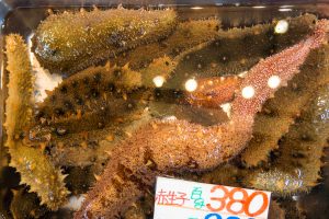 Sea cucumbers in water container  for retail sale in Japanese fresh food market. They are marine animals with a leathery skin.