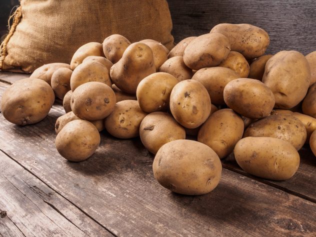 Potatoes From Bag Lying On Wooden Boards