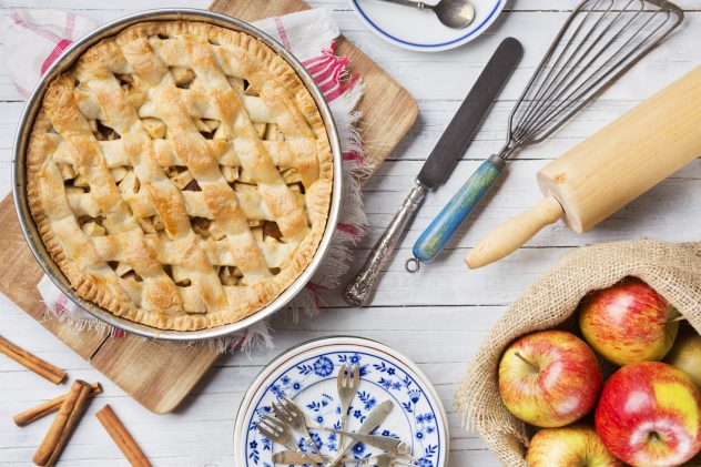 Homemade apple pie and ingredients on a rustic table