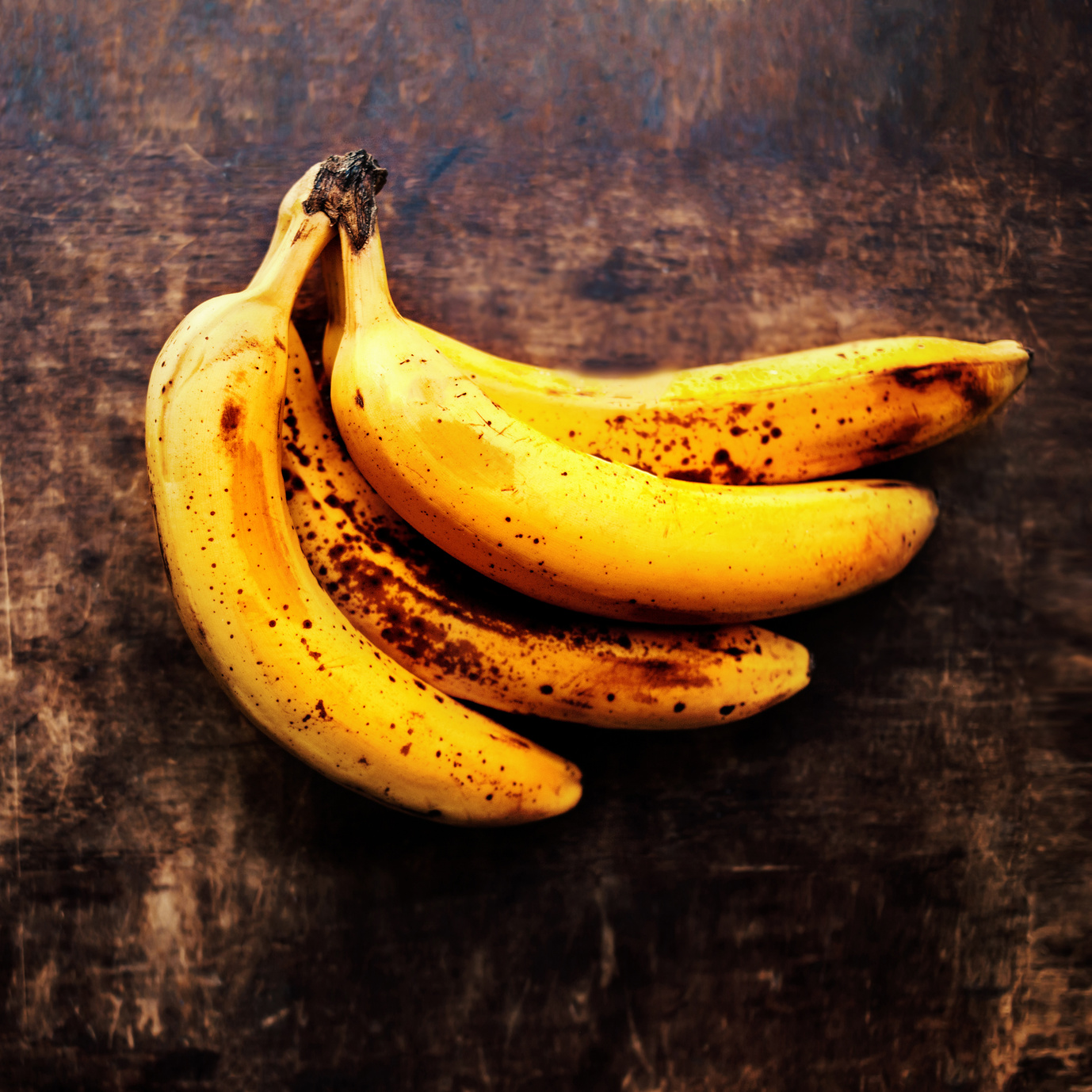 A branch of rotten ripe bananas on vintage wooden background. Overripe banana close up