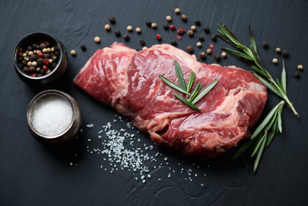 Raw ribeye steak with seasonings, close-up, studio shot