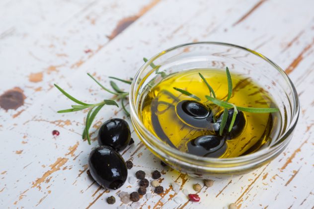 Olive oil with maslines on wood background