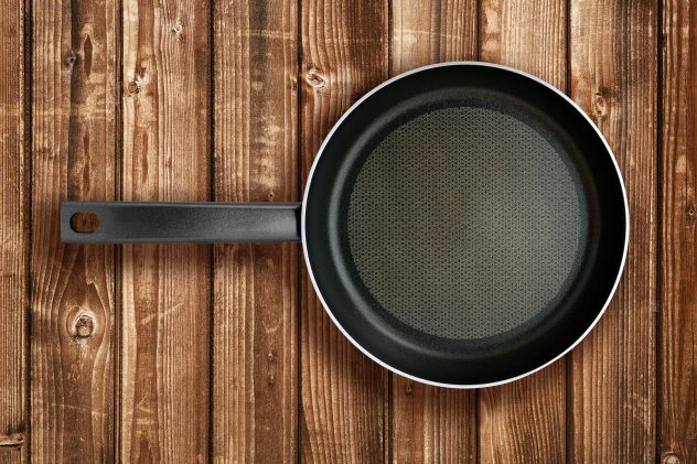 Frying pan on wooden table top view