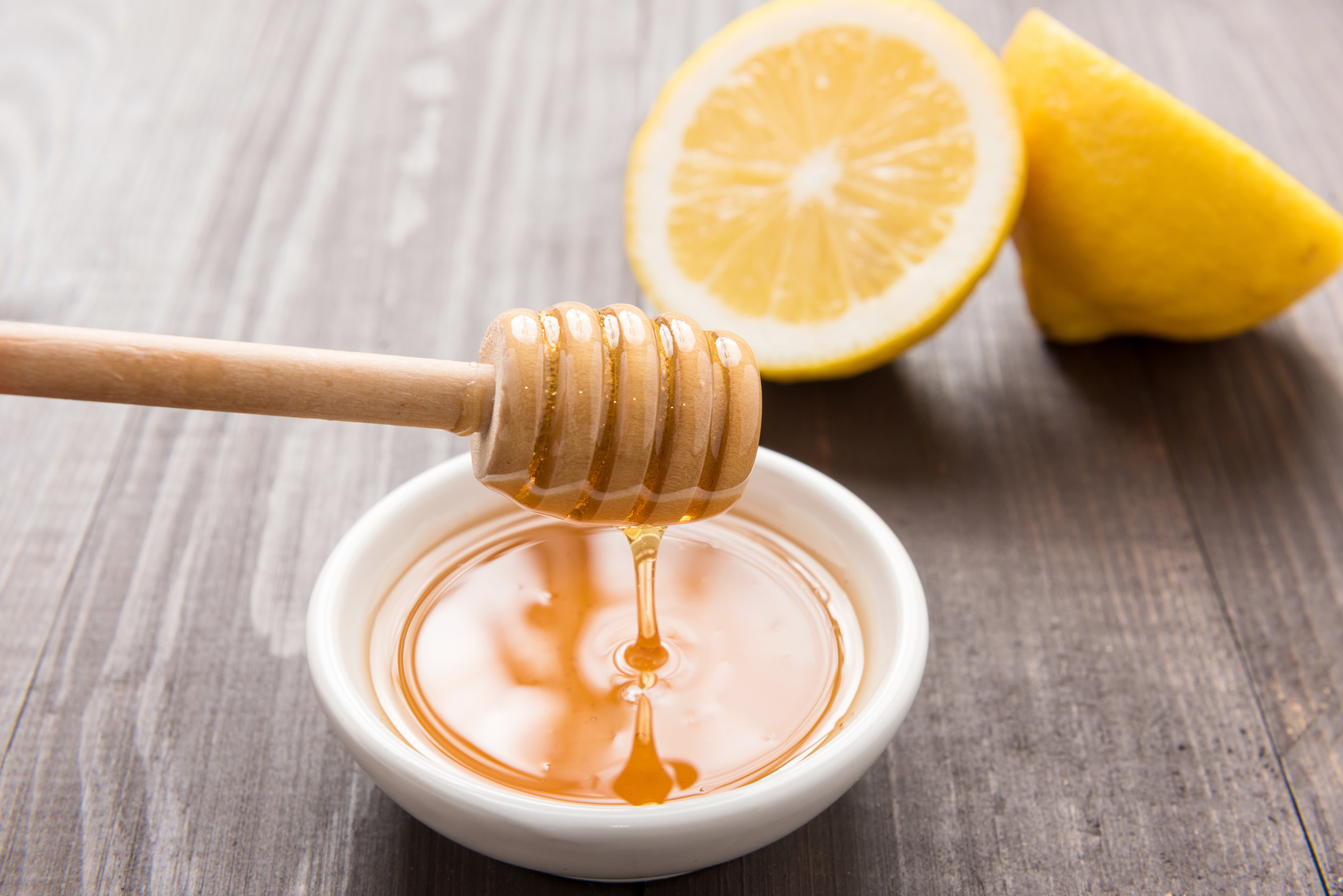 Bowl of sweet honey and lemons on wooden table