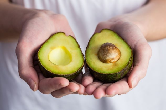 Woman showing fresh avocado