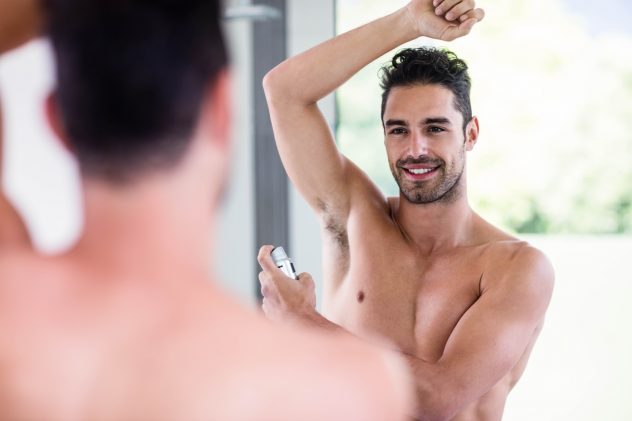 Handsome shirtless man putting deodorant