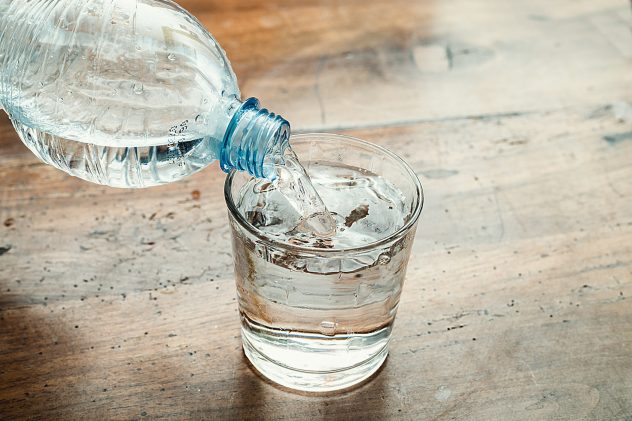 blue water bottle poured into a clear glass