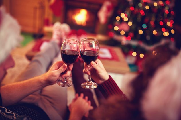 couple with red wine, against xmas tree and fireplace