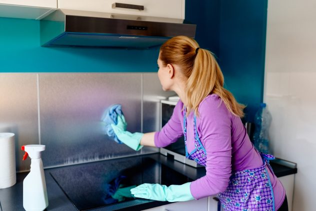 Young woman in rubber gloves cleaning kitchen.