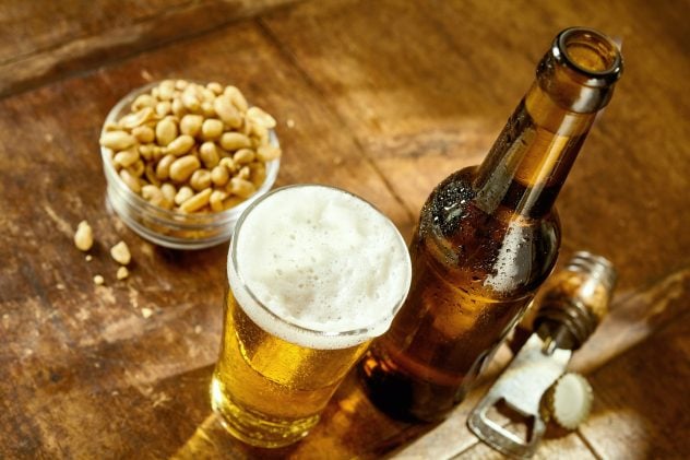 Glass of Beer on Table with Opener and Peanuts