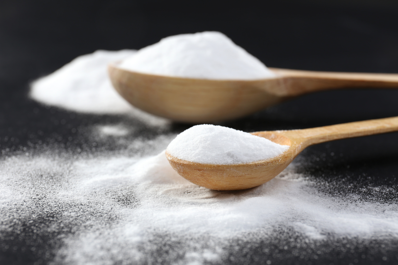 Spoons of baking soda on black background