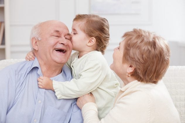 Cute small child is expressing love to grandparents