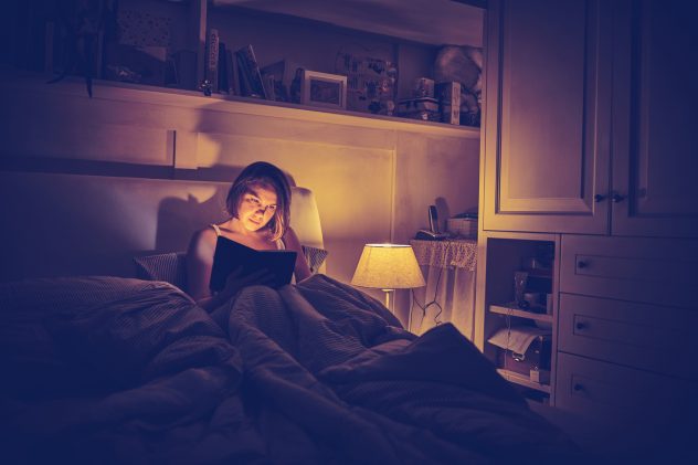 Nainen lukee kirjaa sängyssä
