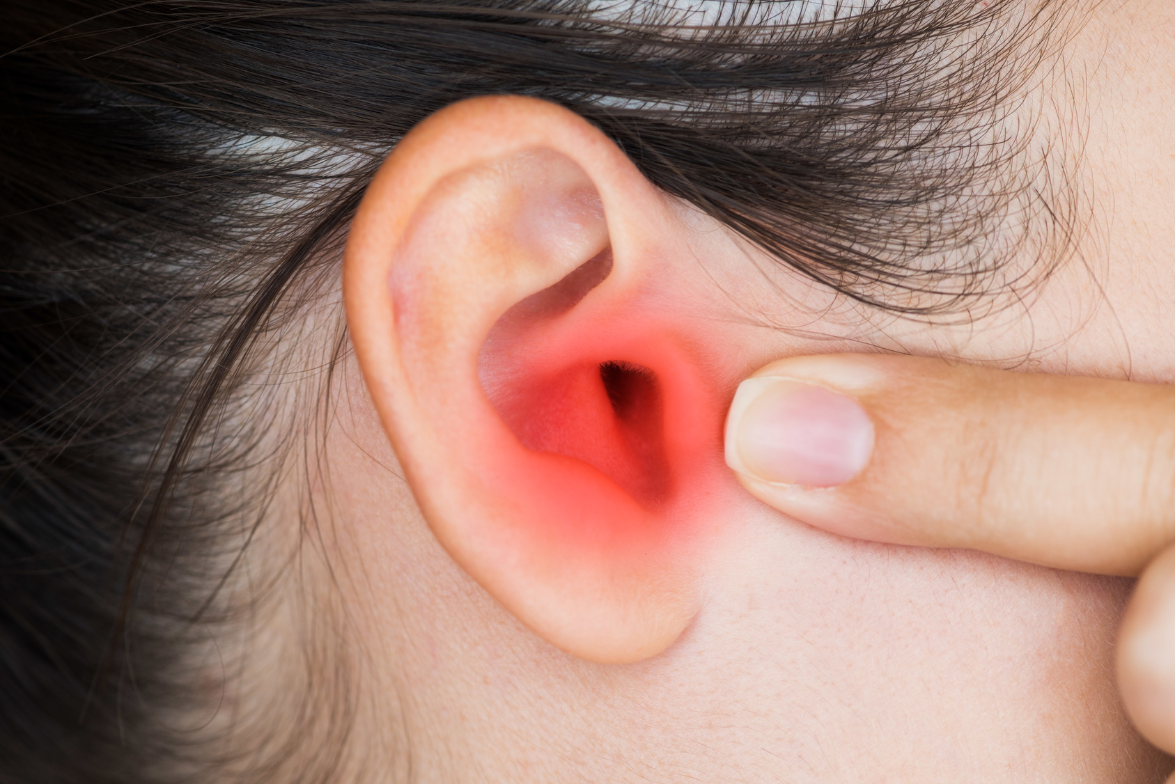 Closeup of a human ear with red painful area - Young woman has pain in the ear