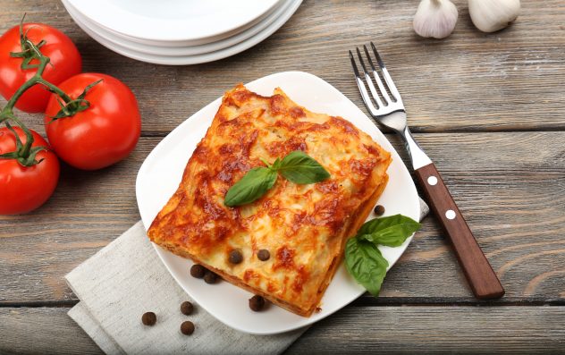 Portion of tasty lasagna on wooden table